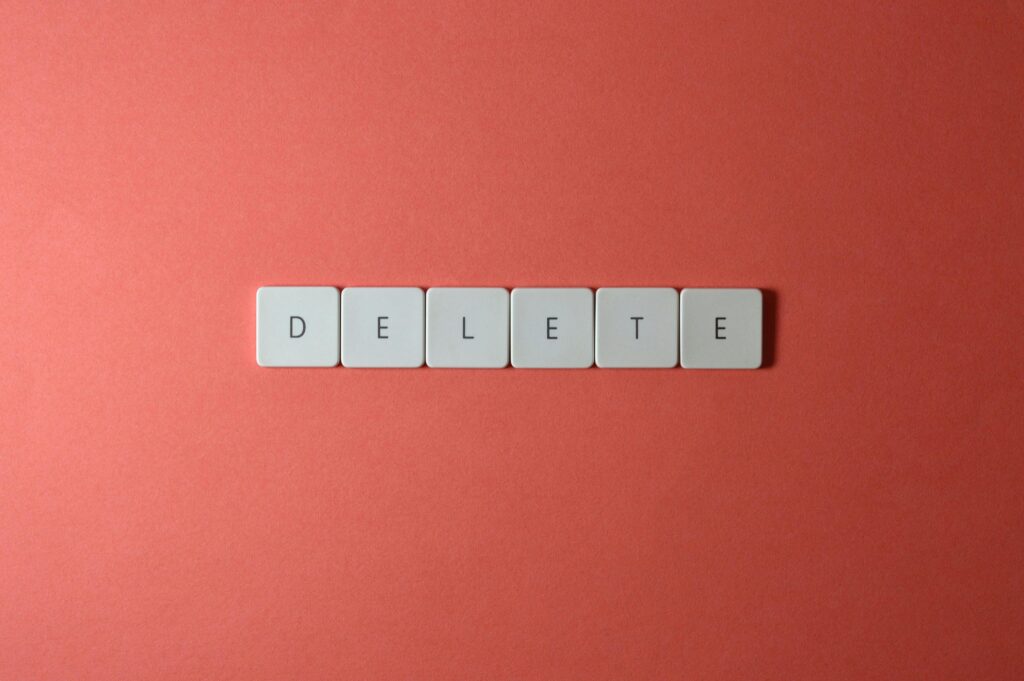 Close-up of keyboard letters spelling 'DELETE' on a coral background, emphasizing digital concepts.
